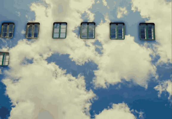 A man runs along a walkway of paving stones across a building facade made of clouds and sky