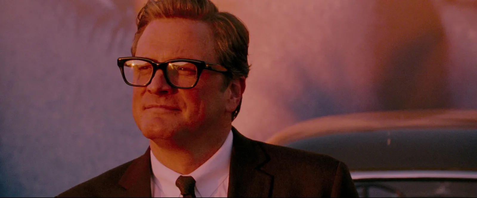 A man in glasses in a warm red close-up