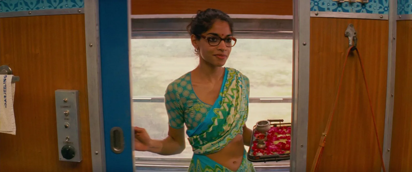 A train stewardess in a turquoise sari walking down a blue corridor