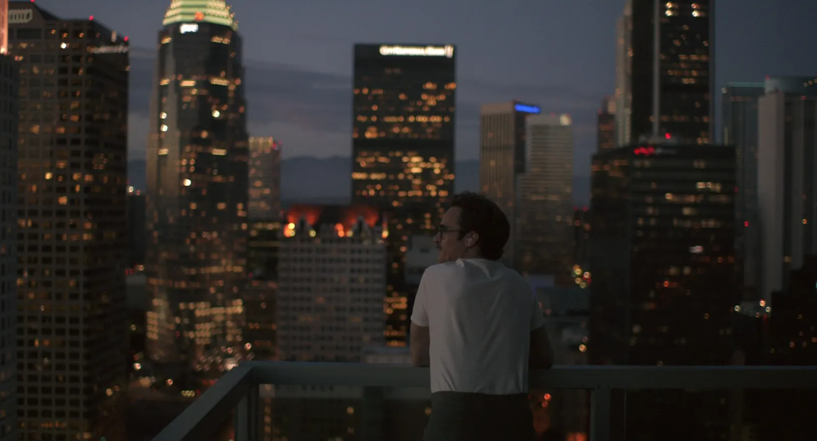 A man looking out over the Los Angeles skyline at dusk