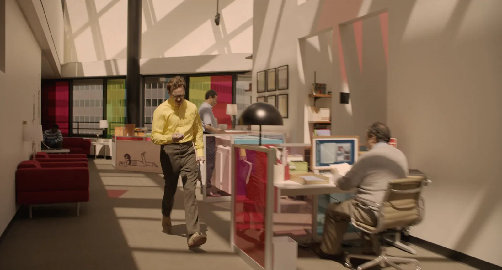 A bright office in pastel pink, red and cream with sunlight pouring through the windows
