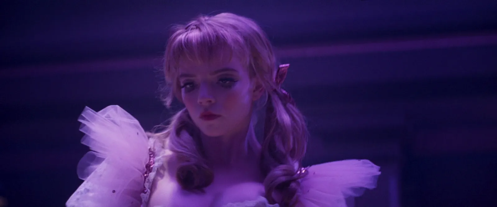 A blonde singer in a lilac tulle dress drenched in violet stage light