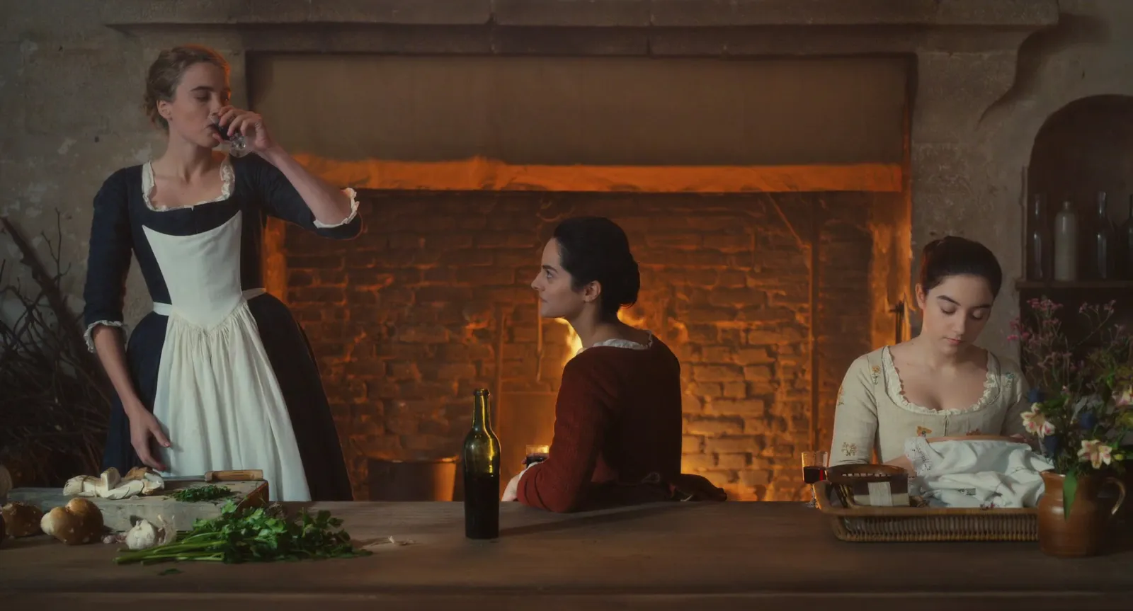 Three women in a candlelit stone kitchen