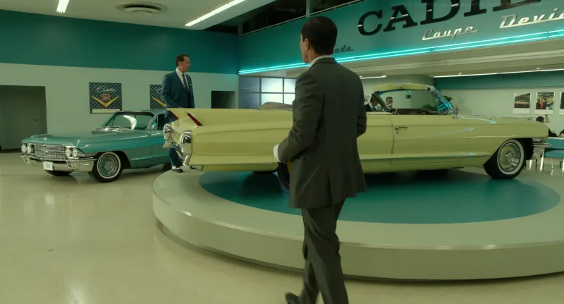 A 1960s car showroom in teal and mint with a cream convertible on a turntable, from The Shape of Water