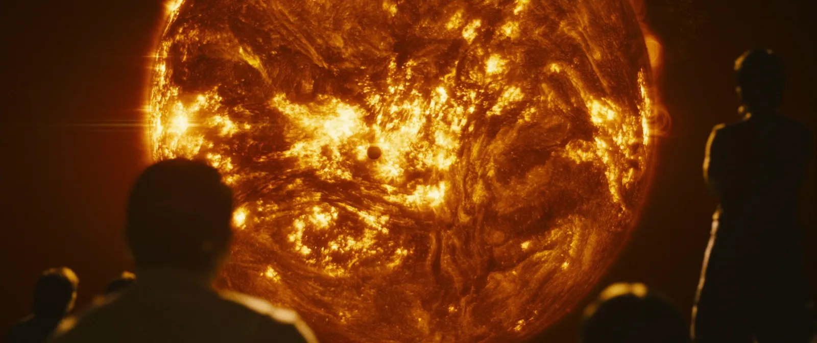 Silhouetted crew watching the churning surface of the sun fill the frame