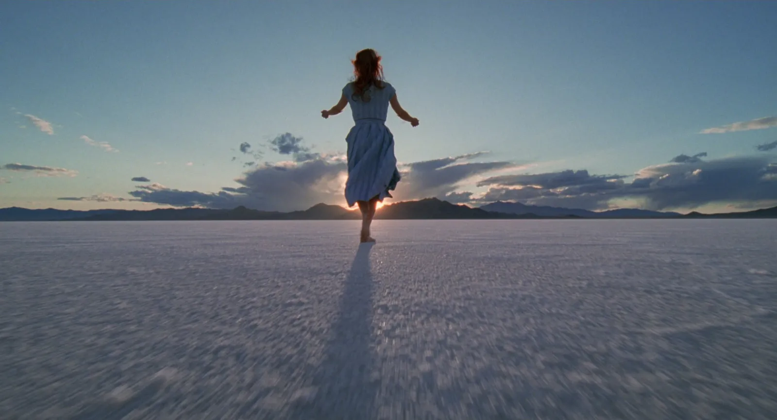 A woman alone on a salt flat at dusk